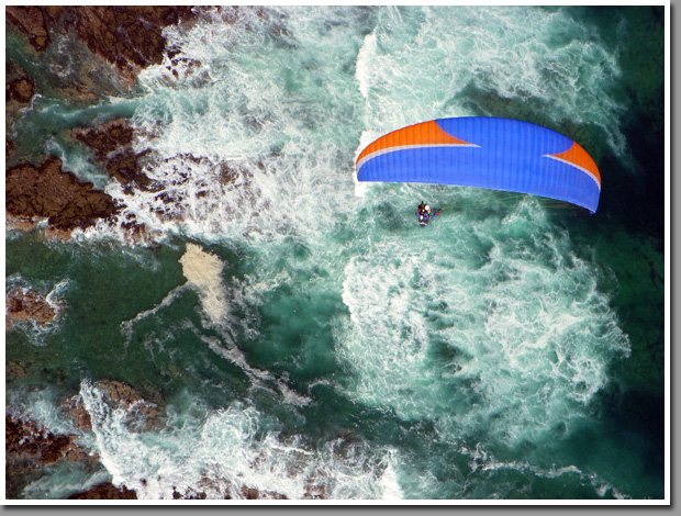 Leo Andrade flying his tandem paraglider over Iquique's coast toward Cavancha beach, Iquique, Atacama Desert, Chile