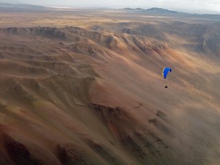 Evening soaring - Bob Janzen from USA flying over high wind mountain desert area called “cementario dos” during one of evening XC flights, Iquique, The Atacama Desert, Chile